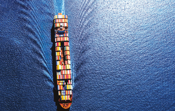 Image of a container ship moving downward on deep blue water 